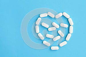 White pills on blue background in heart form.
