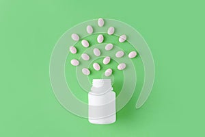 White pills and bottle on green background. Medical pharmacy concept. Probiotics benefits.