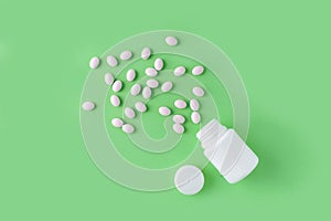 White pills and bottle on green background. Medical pharmacy concept. Probiotics benefits.
