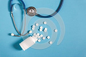 White Pills, Bottle And Stethoscope On Blue Background, Top View. Medicine Healthcare Pharmacy Concept