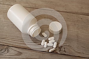 White pills with bottle on wooden table