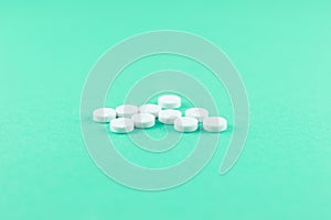 White pills with copy space on aquamarine background. Focus on foreground, soft bokeh