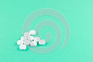White pills with copy space on aquamarine background. Focus on foreground, soft bokeh