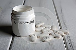 White pills with emoticons with a jar with inscription antidepressant