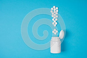 White pills in a exclamation mark poured from a medicine bottle on blue background. Medication and prescription pills. Important i