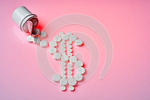 White pills fell out of a still bottle. White pills are laid in the dollar sign on a pink background. Concept for medical
