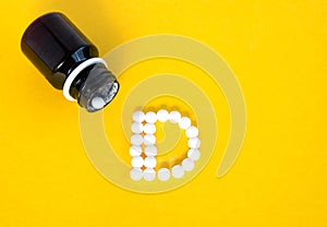 White pills forming shape to D alphabet isolated on yellow background