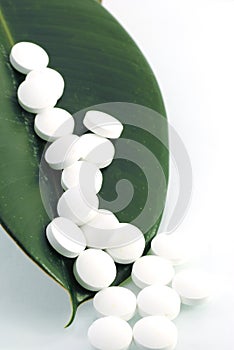 White pills on a green leaf