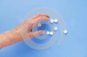 White pills on the hand of an elderly man close-up.
