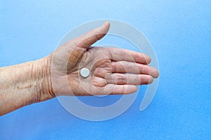 White pills on the hand of an elderly man close-up.