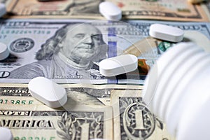 White pills and a medical bottle on one and one hundred dollar bills. Health insurance concept. Medicine and money.