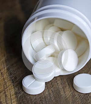 White pills. Medical tablets in white plastic packaging. White pills poured out of the box onto a wooden table.