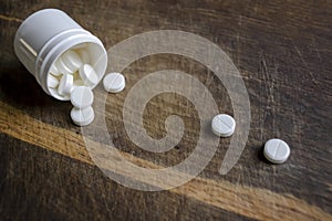 White pills poured out of the box onto a wooden table. White pills. Medical tablets in white plastic packaging.