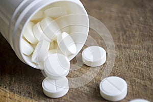 White pills. Medical tablets in white plastic packaging. White pills poured out of the box onto a wooden table.