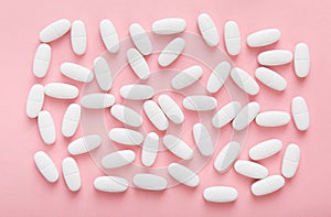 White pills on pink background. Medical concept pattern