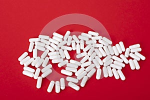 White pills on the red paper background