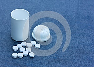 White Pills scattered across a Blue Background and an Open Bottle. Top View Closeup