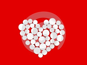 White medicine pills in the shape of a heart on a red background top view with copy space.