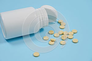 White pills spilling out of a toppled white pill bottle. Isolate