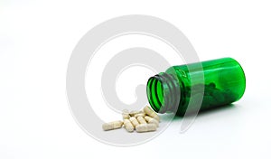 White pills spilling or pour out of green pill bottle isolated on white background with copy space for add text.
