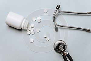 White pills, stethoscope on the doctor`s table. Medicine concept. Research on prescribing the dose of medicinal products. Health