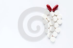 White pills and two red capsules on white background. Pharmaceutical medicament. Antibiotic, painkiller or narcotic, closeup