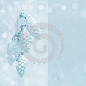 White pine cone ornaments with snow and glitter;  Christmas greeting card in blue silver color, with copy space for your text