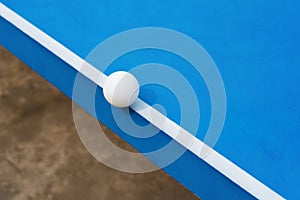 White pingpong ball hits the edge of blue pingpong table
