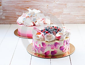 White and pink birhday cake with meringues and fresh berries, raspberries, strawberries and blueberries