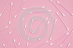 White and pink cotton swabs on pink paper background