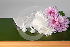 White and pink flowers of chrysanthemum, phone, earphones and book