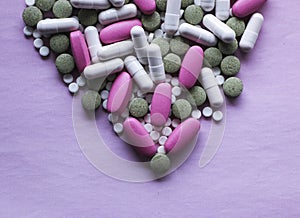 White, pink and green pills on a pink background. multi-colored drugs.