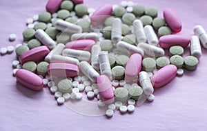 White, pink and green pills on a pink background. multi-colored drugs.