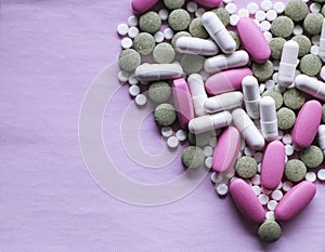White, pink and green pills on a pink background. multi-colored drugs.