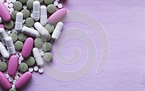 White, pink and green pills on a pink background. multi-colored drugs.