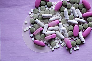 White, pink and green pills on a pink background. multi-colored drugs.
