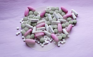 White, pink and green pills on a pink background. multi-colored drugs.