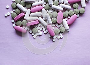 White, pink and green pills on a pink background. multi-colored drugs.