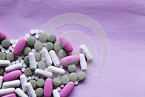 White, pink and green pills on a pink background. multi-colored drugs.