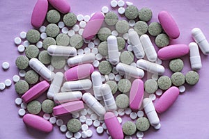 White, pink and green pills on a pink background. multi-colored drugs.