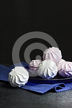 White and pink marshmallow on blue plate on black background