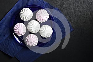 White and pink marshmallow on blue plate on black background