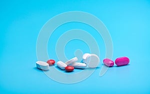 White and pink tablets pills on blue background. Pharmacy banner. Pharmaceutical industry. Health insurance strategy.