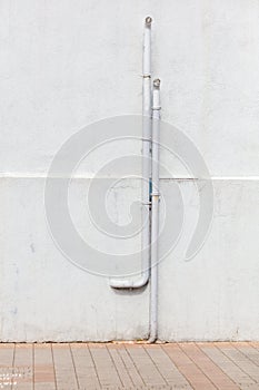 A white pipe is leaning against a wall