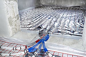 White pipes of underfloor heating systems, arranged in an individual family home on an insulating foil, passing through the founda