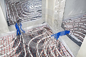 White pipes of underfloor heating systems, arranged in an individual family home on an insulating foil, passing through the founda