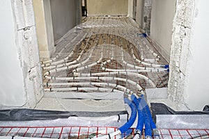 White pipes of underfloor heating systems, arranged in an individual family home on an insulating foil, passing through the founda