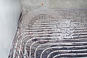 White pipes of underfloor heating systems, distributed in an individual family house on insulating foil.