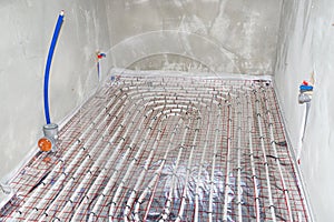 White pipes of underfloor heating systems, distributed in an individual family house on insulating foil.