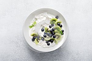 White plain greek yogurt with fresh blueberries and kiwi fruit, top view